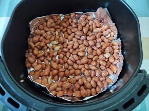 在空气炸锅的炸篮里铺一层锡纸或油纸，然后将花生米拨入，扒平，尽量不要重叠。注意，盆子里的水不要倒进去，不然影响烤干时间。180度先烤5分钟。时间和温度供参考，因为每个人的机器不一样哦。