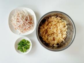 把蟹味棒解冻，撕成丝；把土豆洗净去皮擦成丝，刀工好的话可切成细丝哦～小葱洗净切成葱花。