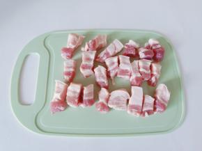 五花肉用温水洗一下，放在案板上切成小块。