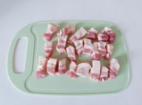 五花肉用温水洗一下，放在案板上切成小块。