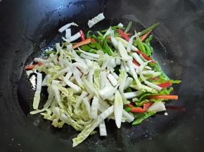 锅烧热，倒入一点油，大概两三汤匙的样子，将辣椒丝、蒜白和大白菜帮子先下锅煸炒至变软，然后盛起备用。这样香一点，脆一点。