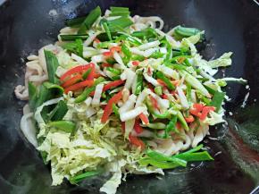 将前面炒好的辣椒丝那些倒入，还有剩下的蒜叶和大白菜叶也倒入，一起翻炒拌匀。