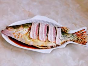 把切好的培根铺在鱼身上。