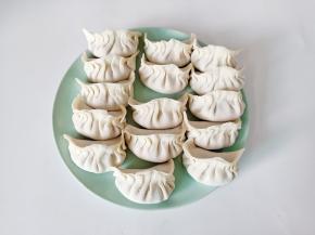 拿一张饺子皮放上肉馅，依次捏上褶皱包起来。