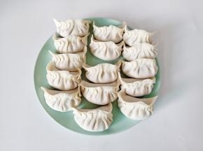 拿一张饺子皮放上肉馅，依次捏上褶皱包起来。