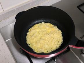 把混合好的面条倒入平底锅中，摊成圆饼，保持小火。