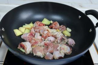 锅烧热之后，倒入适量花生油，把大蒜、生姜煸炒香，接着倒入鸡肉炒至焦黄、放入香菇翻炒。