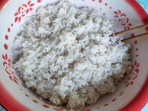 分几次将滤干水的糯米倒入盆中，倒一层糯米，撒一点酒曲拌匀。