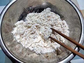 一边倒水，一边用筷子将面粉搅成絮状。