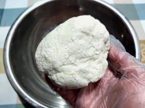 用手将面絮揉成一个面团。刚开始，不好揉，没关系，揉成团就行。看这是第一次揉，还有很多面絮。盖上放一边静置10-30分钟。一般十几分钟后就好揉了，盖上是防止表面风干。