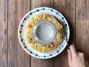 取一个圆盘，在圆盘中间扣一个碗，把炒饭围着碗摆好，用勺子整成一个圆环形。