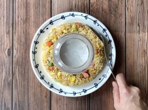 取一个圆盘，在圆盘中间扣一个碗，把炒饭围着碗摆好，用勺子整成一个圆环形。