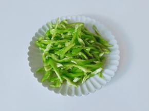 尖椒去蒂对半切开，挖出里面的籽，再切成细丝。
