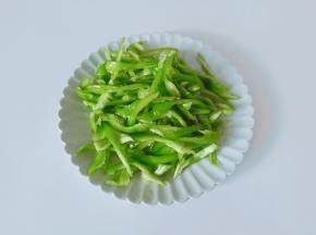 尖椒去蒂对半切开，挖出里面的籽，再切成细丝。