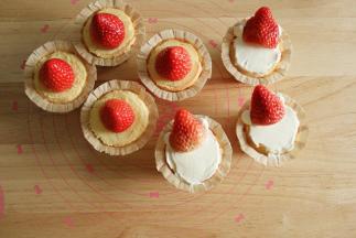 步骤11、开始凹造型。要放草莓，所以纸杯凸起的部位需要修平。一半放上整颗草莓，草莓底部切掉一些，抹上一点淡奶油放平。另一半先用抹刀抹上一层淡奶油，尽量抹平一些，再挤上4个淡奶油小圆球，然后草莓切掉一点底部，对半切开，靠在上面，让草莓立起来一些。