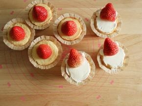 步骤11、开始凹造型。要放草莓，所以纸杯凸起的部位需要修平。一半放上整颗草莓，草莓底部切掉一些，抹上一点淡奶油放平。另一半先用抹刀抹上一层淡奶油，尽量抹平一些，再挤上4个淡奶油小圆球，然后草莓切掉一点底部，对半切开，靠在上面，让草莓立起来一些。