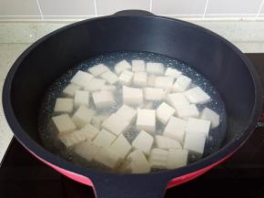 水沸后加入少量的盐，放入豆腐煮约1分钟，焯过水的豆腐捞出备用。