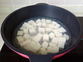 水沸后加入少量的盐，放入豆腐煮约1分钟，焯过水的豆腐捞出备用。
