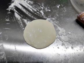 取一个小剂子，用擀面杖擀成直径10厘米左右圆片，和饺子皮一样，中间厚边缘薄一点。