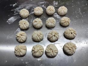 包子全部包好后，底部粘一点点干粉，不然醒发后容易粘在案板上不好拿。静置醒发10-30分钟，记得最好盖上，防止包子表面风干。醒到包子能明显看到涨大一点。时间视室温而定，室温高醒发时间短，室温低时间长。