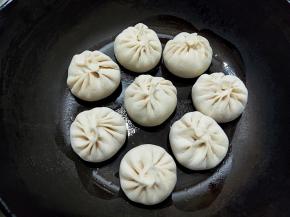 不粘锅倒少量油，刚刚过锅底部就可以，烧热，将包子排好，稍微留一些空隙。中小火加热，火不要太大，容易煎糊了。