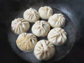 沿着锅边淋入半碗水，不能直接淋在包子上，不然影响包子的涨发。水的高度不要超过包子高度的1/3，盖上小火焖。中间不能开盖，等听到滋滋声水差不多要烧干了，才能开盖。如果不放心包子没熟，就再加一次水。我一般都是加两次水的。