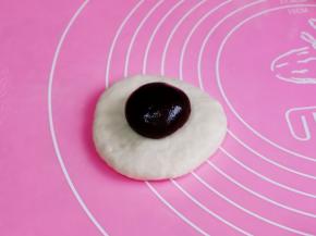 取一块面团，擀圆饼，再放上豆沙馅，包子手法捏起来，收口捏紧朝下。