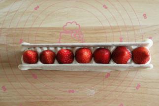 糯米皮撒上一些熟糯米粉，抖掉多余的糯米粉，擀开成长方形，放入模具中，尽量平整一些。底部放入一条蛋糕胚，挤上一层奶油，垂直放上草莓。