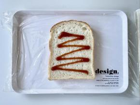 取一张保鲜膜，放上吐司片，先挤上番茄酱，各种你喜欢的酱料都可以。