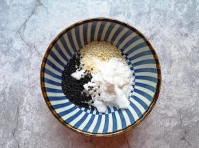 小碗里放入糖，加入玉米淀粉、熟白芝麻和熟黑芝麻。