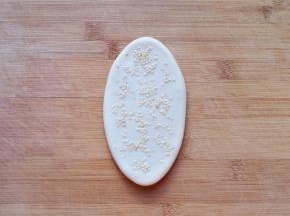 撒上熟白芝麻，用擀面杖轻轻擀一下，让芝麻粘在上面，不容易掉落，一个空心芝麻饼生胚就做好了，依次做完剩下的饼。