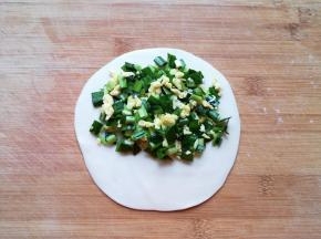 取一个小剂子压扁，擀成圆形，将馅料放在一边（如图）。