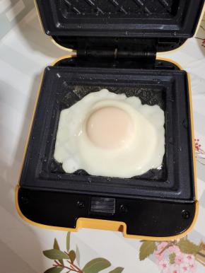 比依三明治机提前预热，刷适量的油，打入一个鸡蛋煎熟！(盖上盖子大约2分钟左右就好！)