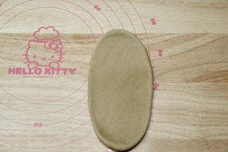 取一松弛好的面团，拍扁，擀开成长条形。