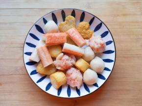 取一部分火锅丸子，蟹味棒去掉包装从中间切开，一起用水冲洗一下备用。