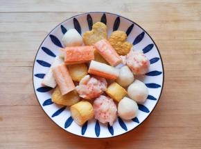 取一部分火锅丸子，蟹味棒去掉包装从中间切开，一起用水冲洗一下备用。