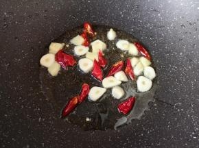 炒锅内倒适量的食用油烧热，下入大蒜、生姜和干红辣椒炒香。
