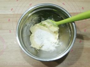 软化好的黄油倒入糖粉，用刮刀先按压混合，防止糖粉飞溅。