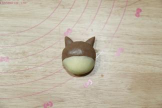 2号柴犬，20克可可面团搓圆按扁，4克白色面团按扁也是同样方法，贴在可可面团的下半部分，耳朵水平贴合，这样烤的时候不会掉。想要鼻子的话，1克白色面团搓圆按扁装上去即可。