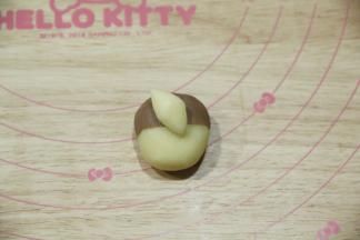 1.5克白色面团搓成橄榄形，斜着贴在略靠上的位置，作尾巴。