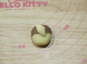 1.5克白色面团搓成橄榄形，斜着贴在略靠上的位置，作尾巴。