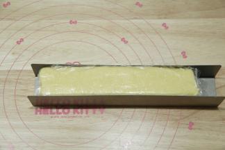 U型饼干模具中，放入保鲜膜，将混合好的面团放入，整形成一条长方形饼干胚。一定要按压均匀，不要有孔洞。