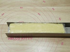 U型饼干模具中，放入保鲜膜，将混合好的面团放入，整形成一条长方形饼干胚。一定要按压均匀，不要有孔洞。