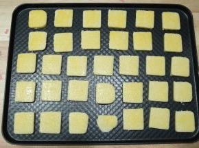 裹好保鲜膜冷冻30分钟定型。预热烤箱上下180度，取出定型好的胚切块，一条可以切出32块饼干胚。均匀排列入烤盘（头尾不平整的可以切掉，一起放入烤），半个蛋黄过筛后加一点牛奶，搅匀成蛋黄液，均匀刷一层在饼干胚上。