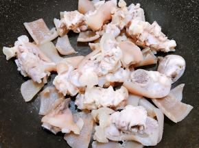 冲洗干净后猪蹄放入锅里，猪皮用刀划去肥肉冲洗干净后放入锅里，加入1小勺盐把水份炒干
