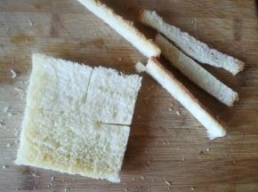 吐司切除四边，用擀面杖压一下。吐司切四边。中间不切段。