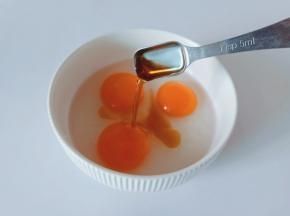 把三个鸡蛋打入碗里，加入料酒一勺。