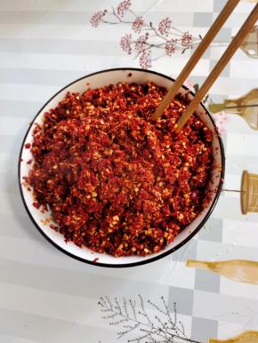 粗辣椒面里面倒入适量的开水烫一下，搅拌均匀，以免放进油锅里往外冒油！(也可以用干辣椒在水中煮十分钟，煮软后捞出，用料理机打碎！)