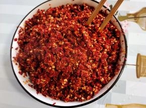 粗辣椒面里面倒入适量的开水烫一下，搅拌均匀，以免放进油锅里往外冒油！(也可以用干辣椒在水中煮十分钟，煮软后捞出，用料理机打碎！)