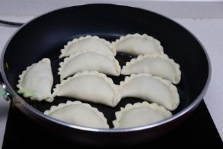 平底锅烧热，倒入适量的适量花生油，均匀码入韭菜盒子、中小火煎至外皮焦黄。